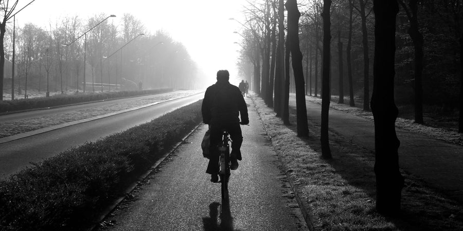 Cycliste sur un vélo de route, photographié en noir et blanc dans la brume